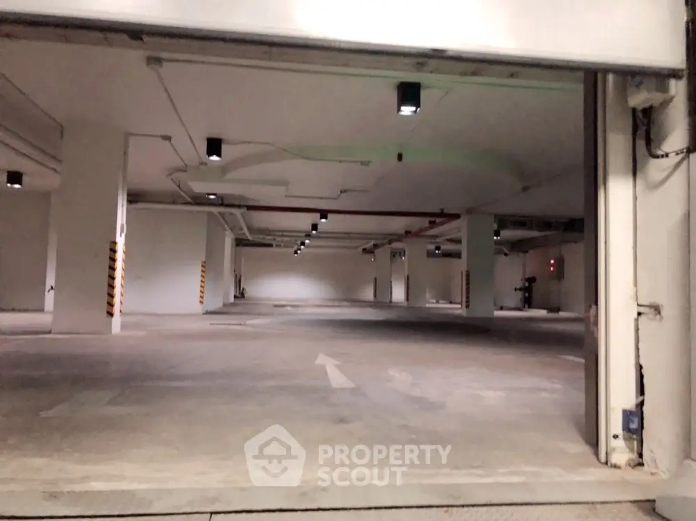 Spacious underground parking facility in a modern residential building, featuring ample lighting and clear directional markings.