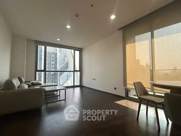 Spacious modern living room with large windows and city view, featuring elegant furniture and natural light.