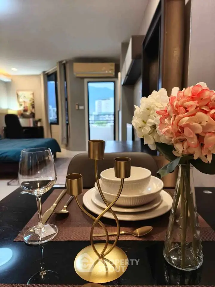 Stylish dining setup in modern apartment with city view, featuring elegant tableware and floral decor.