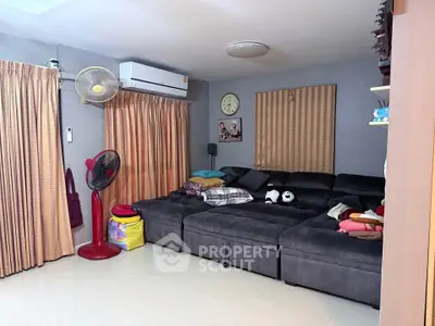 Cozy living room with plush sectional sofa and air conditioning, perfect for relaxation.