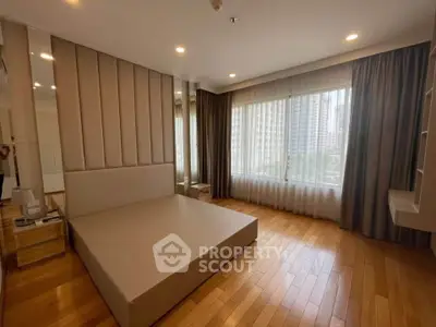 Spacious modern bedroom with large windows and wooden flooring in urban apartment.