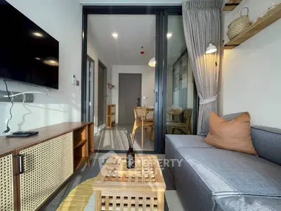 Modern living room with stylish decor and open view to dining area, featuring cozy seating and natural light.