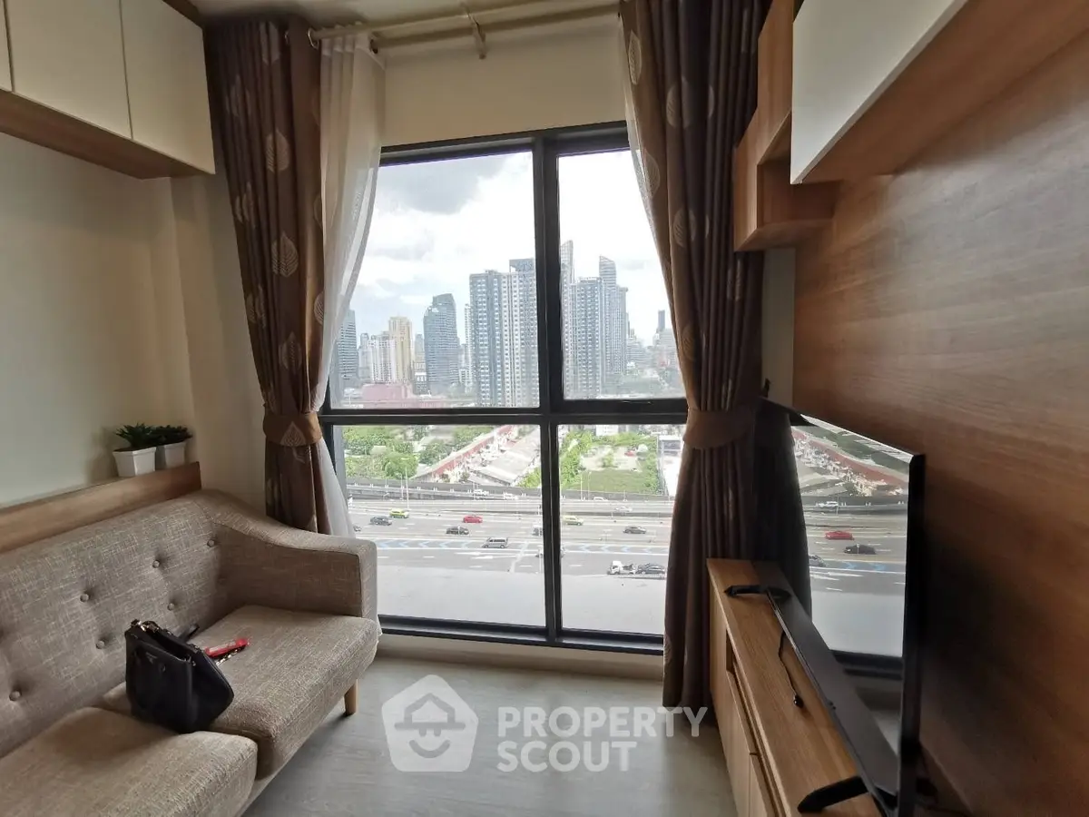 Modern living room with city view, featuring stylish furniture and large window.