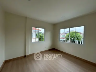 Spacious empty room with large windows and wooden flooring in a modern home