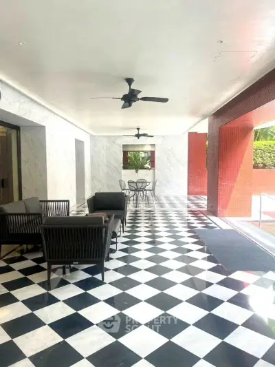 Elegant covered outdoor space with stylish seating and checkered flooring in a modern building.