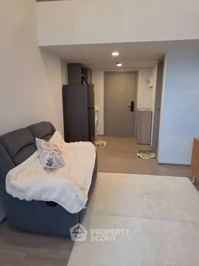 Modern living room with cozy sofa and sleek kitchen appliances in open layout apartment.