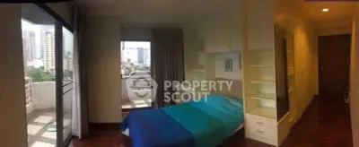 Cozy bedroom with balcony view in urban apartment, featuring built-in shelves and modern decor.
