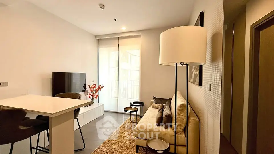 Modern living room with cozy sofa, stylish decor, and natural light from large window.
