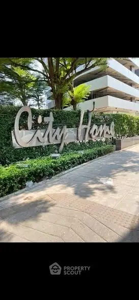 Modern building entrance with lush greenery and stylish signage.