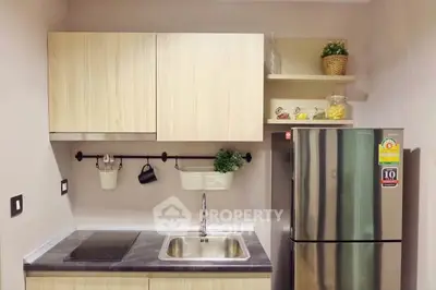 Modern kitchen with sleek cabinetry and stainless steel fridge in a compact layout.