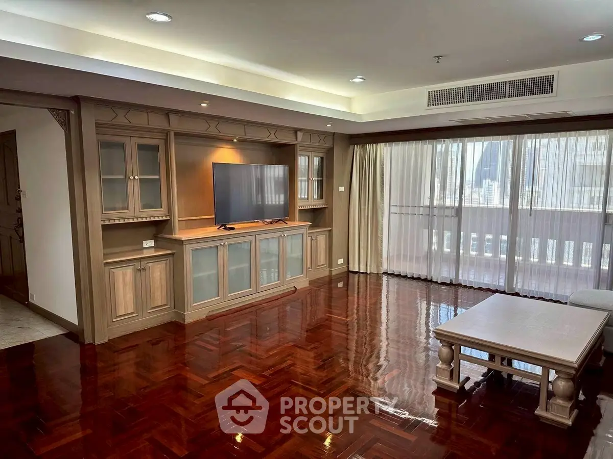 Spacious living room with elegant wooden flooring and built-in entertainment center