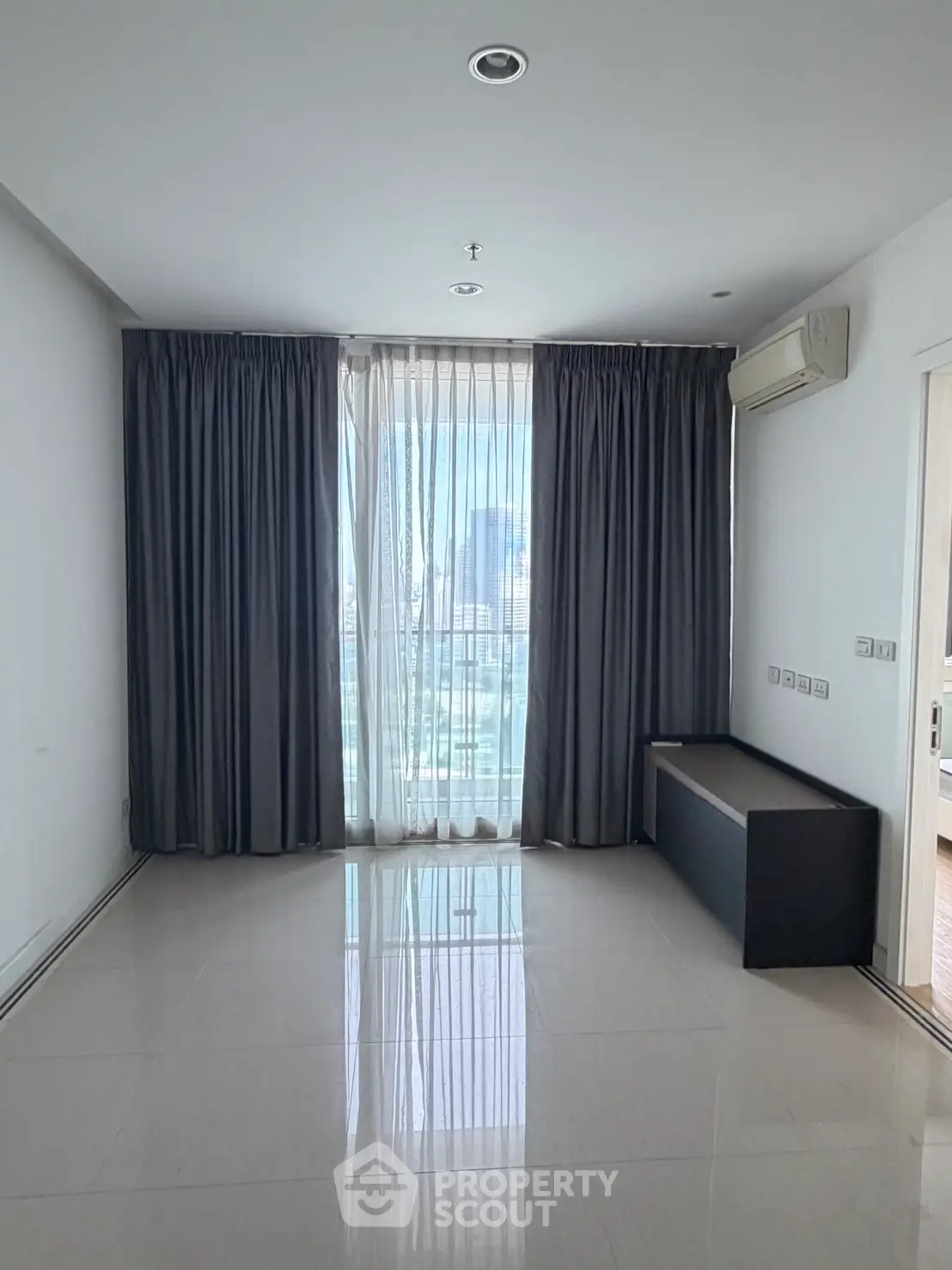 Spacious modern living room with large window and city view, featuring sleek tile flooring and elegant curtains.