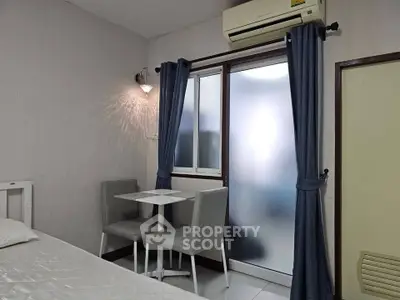 Cozy bedroom with dining nook and air conditioning, perfect for compact living.