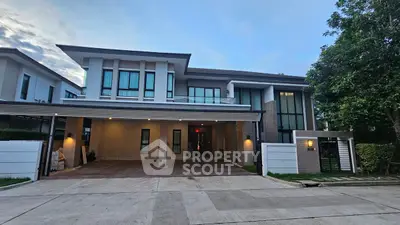 Modern two-story house with large windows and spacious driveway in a serene neighborhood.