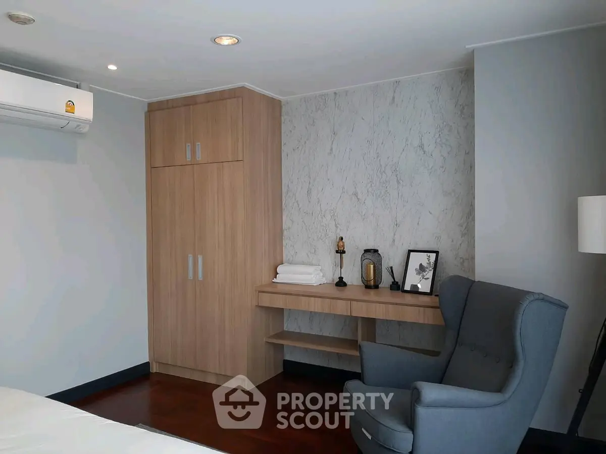 Modern bedroom with stylish armchair and wooden wardrobe, perfect for cozy living.