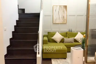 Stylish living room with green sofa and modern staircase