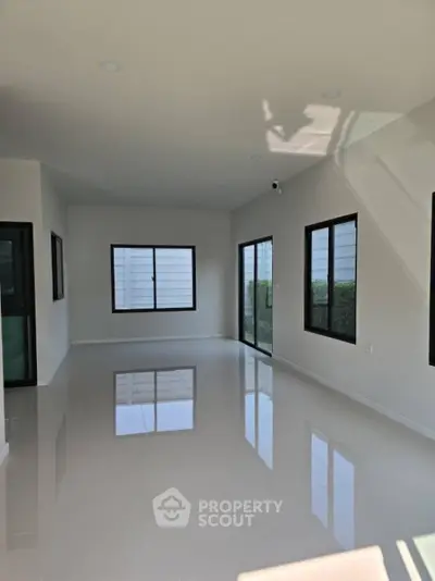 Spacious modern living room with large windows and glossy tiled floor