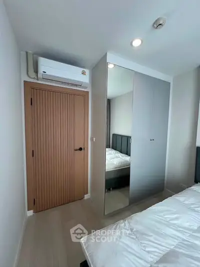 Modern bedroom with mirrored wardrobe and air conditioning unit