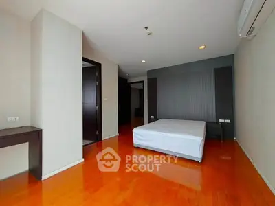 Spacious bedroom with wooden flooring and modern design in a luxury apartment.