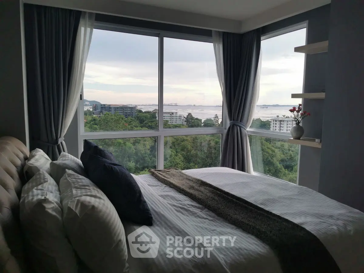 Luxurious bedroom with stunning panoramic view of cityscape and greenery.