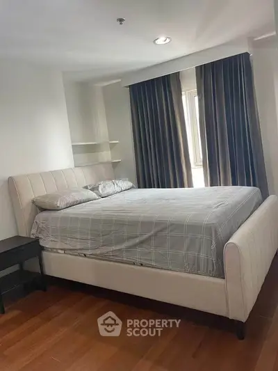 Spacious bedroom with elegant bed and natural light from large window.