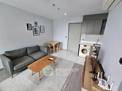 Modern living room with cozy sofa, dining area, and compact kitchen featuring washing machine.