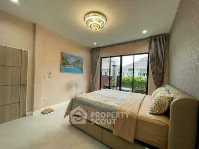 Spacious bedroom with elegant decor and large window offering garden view in modern home.