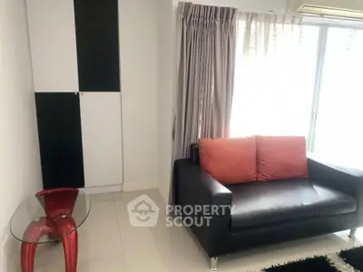 Modern living room with sleek black sofa and glass table, featuring stylish decor and natural light.