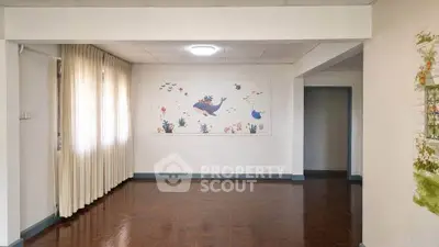 Spacious living room with wooden flooring and whimsical wall art, perfect for family gatherings.