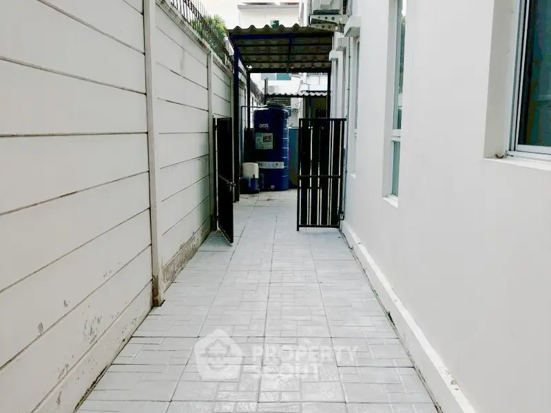 Narrow exterior walkway with tiled flooring and gated entrance