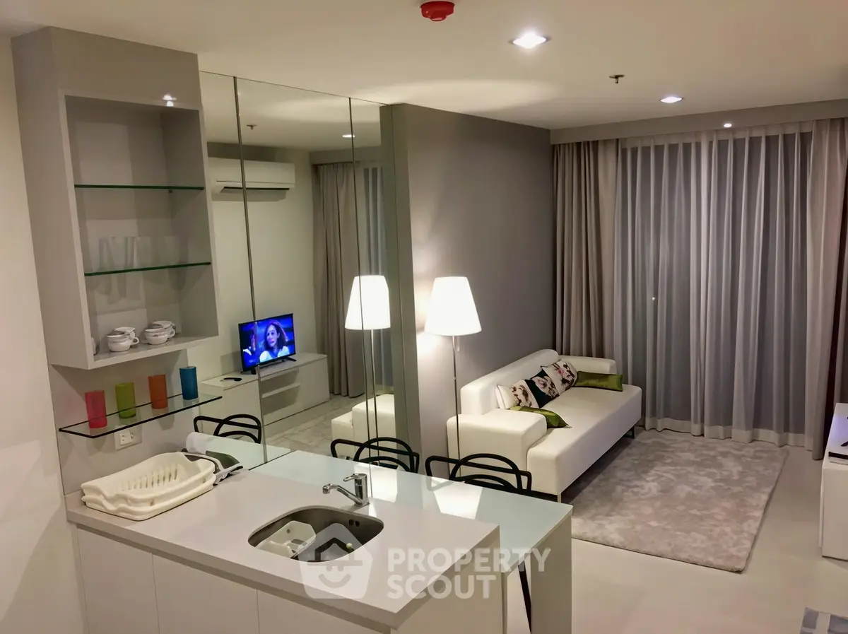 Modern living room with open kitchen, sleek design, and cozy ambiance in a stylish apartment.