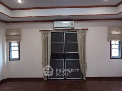 Spacious room with elegant wooden flooring and air conditioning, perfect for comfortable living.