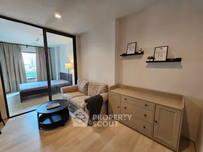 Modern living room with cozy sofa and stylish decor adjacent to a bedroom with natural light.