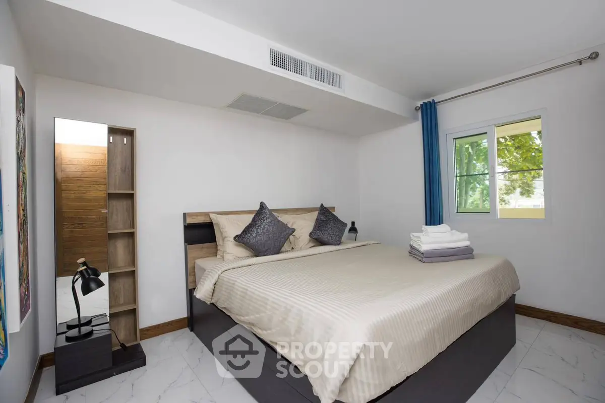 Modern bedroom with stylish decor and natural light in a cozy apartment.