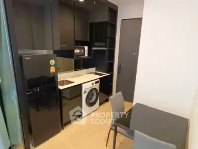 Modern compact kitchen with sleek black cabinets and integrated appliances in a stylish apartment.
