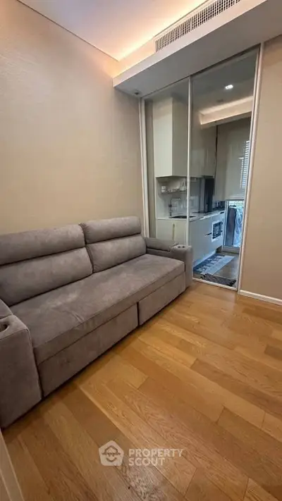 Cozy living room with modern sofa and sliding glass doors leading to a compact kitchen.