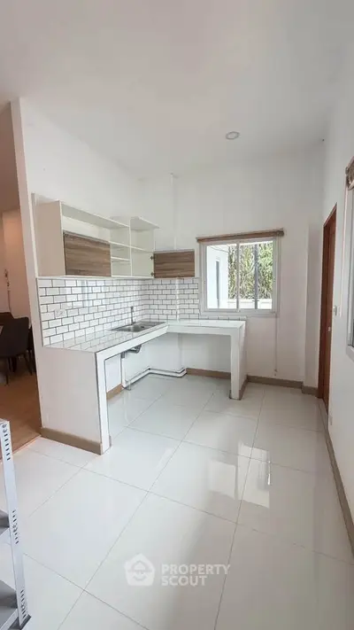 Modern kitchen with sleek white tiles and open layout, perfect for culinary enthusiasts.