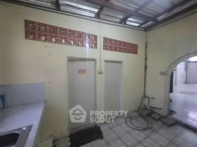 Spacious kitchen area with tiled flooring and unique wall design, perfect for renovation.