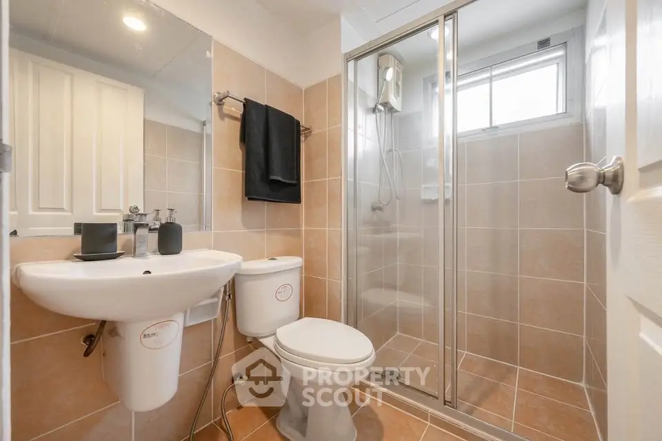 Modern bathroom with glass shower, sleek sink, and tiled walls in a cozy real estate property.