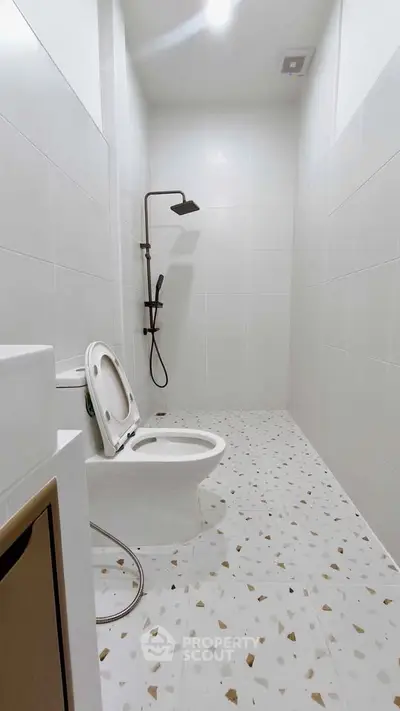 Modern minimalist bathroom with sleek shower and white tiled walls.