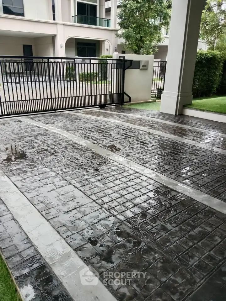 Modern residential entrance with sleek gate and paved driveway