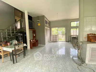Spacious open-plan living area with large windows and tiled flooring, perfect for family gatherings.