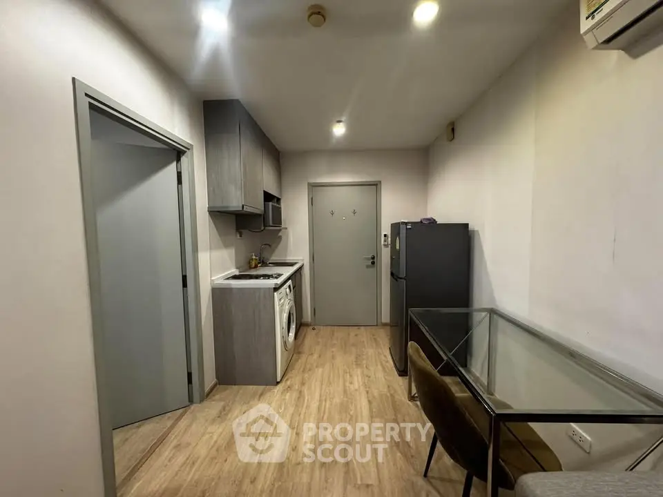Modern apartment kitchen with sleek cabinetry and integrated appliances, featuring a compact dining area.