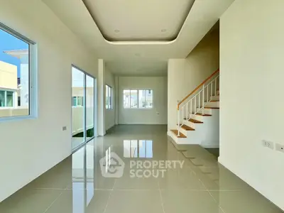 Spacious modern living room with glossy tiled floors and staircase, abundant natural light.