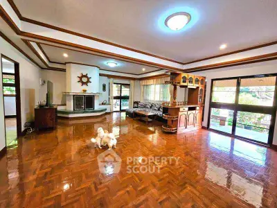 Spacious living room with wooden flooring and large windows for natural light.