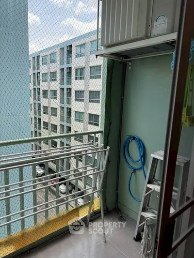 Compact balcony with safety netting and utility setup in urban apartment.