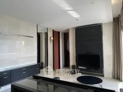 Modern living room with sleek black and white decor, featuring a wall-mounted TV and stylish furnishings.