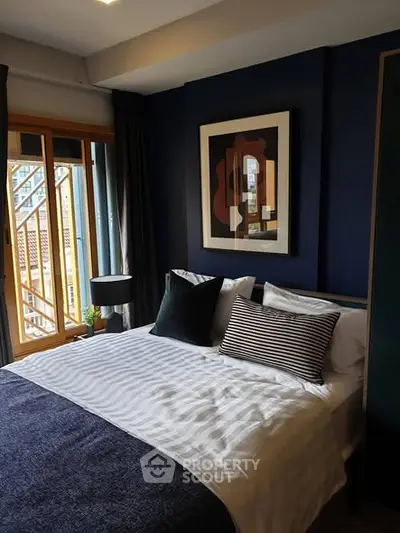 Stylish bedroom with modern decor and large window offering natural light.