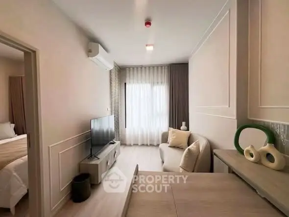 Modern living room with elegant decor and natural light, featuring a cozy sofa and flat-screen TV.