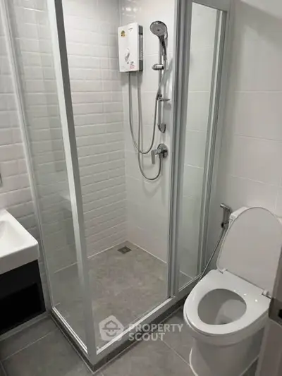 Modern bathroom with glass shower enclosure and sleek fixtures in a contemporary apartment.